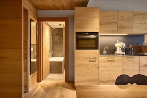 A modern kitchen with wooden cabinetry, a built-in oven, and a coffee machine. - 8028 Sky Residence 28 (Schröcken)