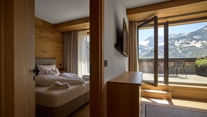 Ein Schlafzimmer mit Bett, Schreibtisch und Blick auf Berge durch große Fenster.
