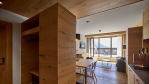 Eine moderne Küche mit Holzausstattung, einem Essbereich mit Tisch und Stühlen und einem großen Fenster mit Blick ins Freie.