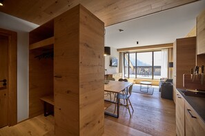 Eine moderne Küche mit Holzausstattung, einem Essbereich mit Tisch und Stühlen und einem großen Fenster mit Blick ins Freie.