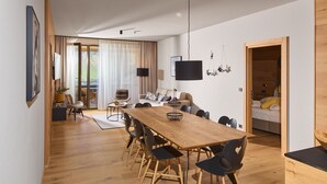 A modern living space with a wooden dining table, black chairs, a sofa, and a TV mounted on the wall. - 8030 Mountain Residence Grand 30 (Schröcken)