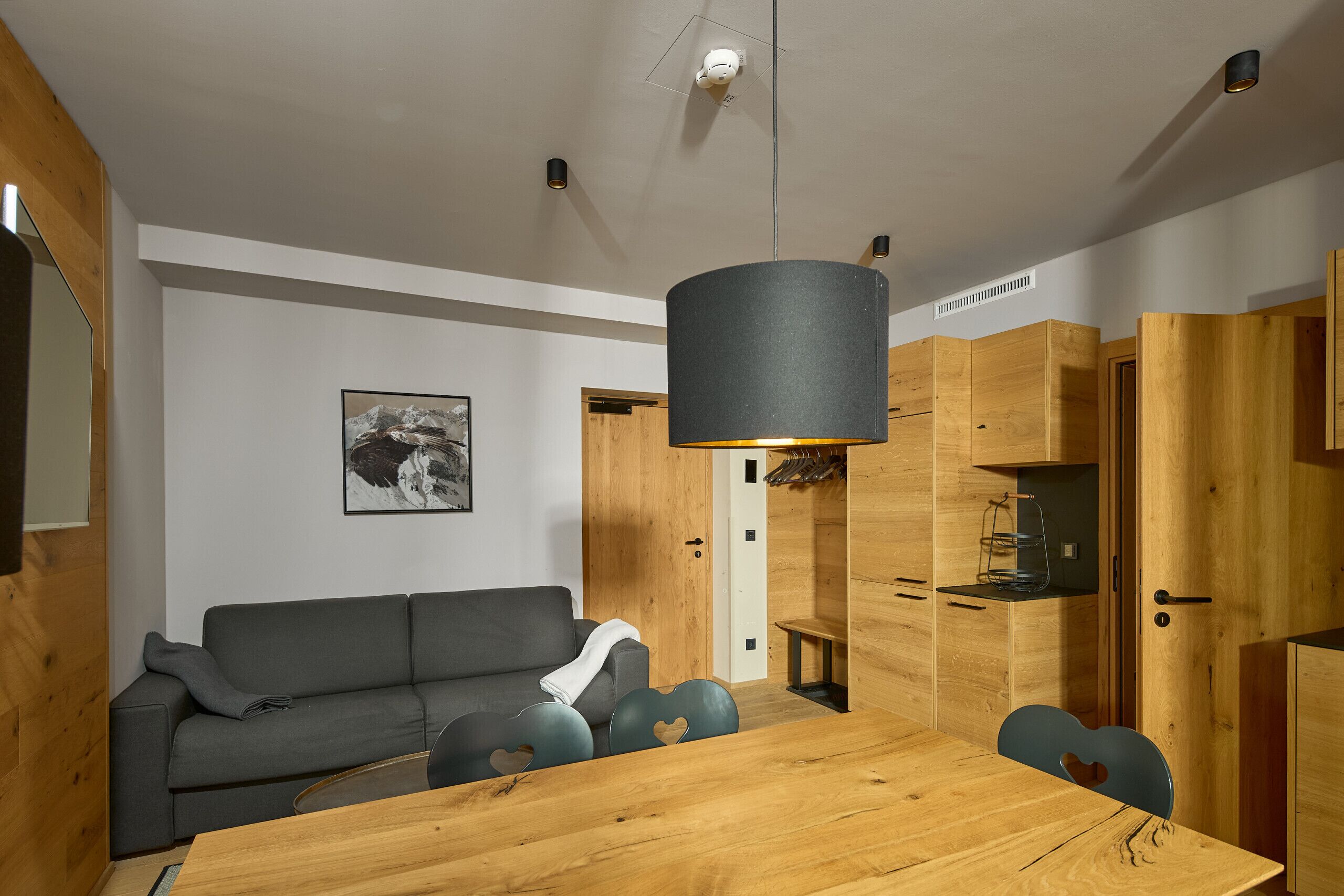 Una cocina moderna con armarios de madera, una mesa de comedor y un sofá gris.