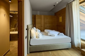 Ein modernes Schlafzimmer mit Bett, Holz-Kopfteil und Blick ins Freie.