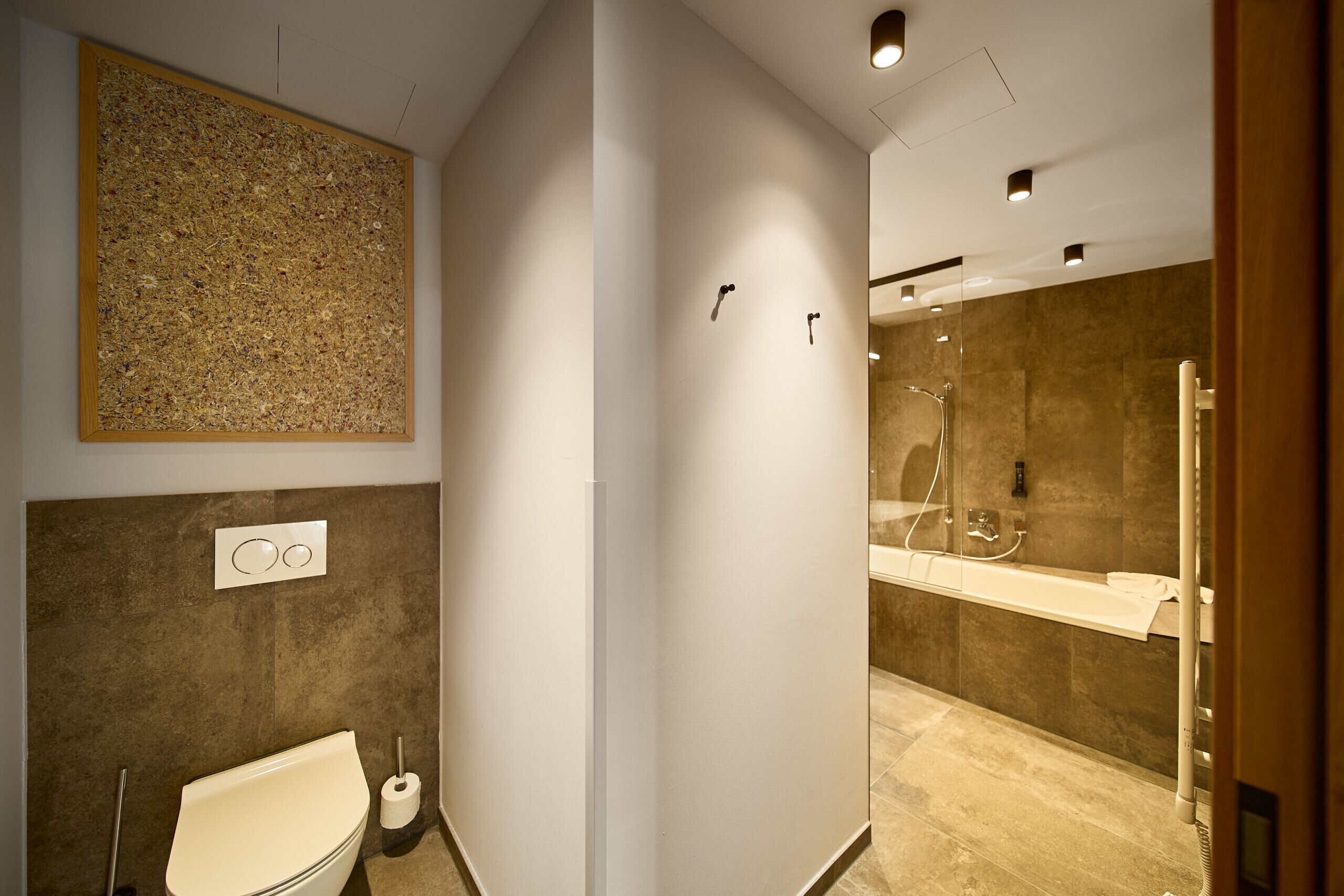 Un baño moderno con inodoro, ducha y un espejo grande.