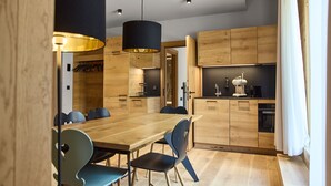 A modern kitchen with wooden cabinets, a dining table with chairs, and a built-in oven. - 8031 Sky Residence 31 (Schröcken)