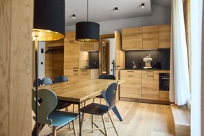 Eine moderne Küche mit Holzausbau, einem Esstisch mit Stühlen und einem Einbauofen.