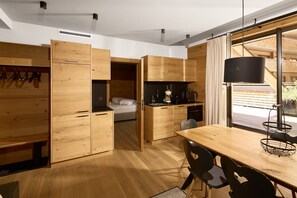 Cocina compacta con armarios de madera, una mesa de comedor con sillas y un ventanal con vistas al exterior.