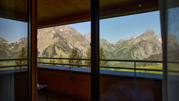 A room with a large window offering a mountain view. - 8033 Alpin Retreat 33 (Schröcken)