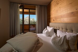 Ein Hotelzimmer mit Bett, einem Fenster mit Vorhängen und Blick auf Berge.