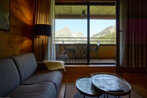 Ein Zimmer mit einer Couch, einem kleinen Tisch und einem Balkon mit Bergblick.