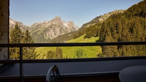 A mountain landscape through a window with a chair and a table visible in the foreground. - 8033 Alpin Retreat 33 (Schröcken)