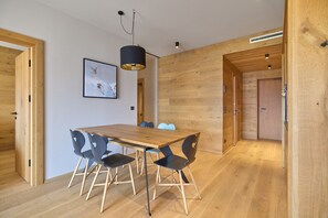 Ein moderner Essbereich mit einem Holztisch und Stühlen, einer Pendelleuchte und einem gerahmten Bild an der Wand.