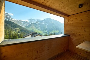 Eine Holzhütte mit einem großen Fenster mit Blick auf eine gebirgige Landschaft.
