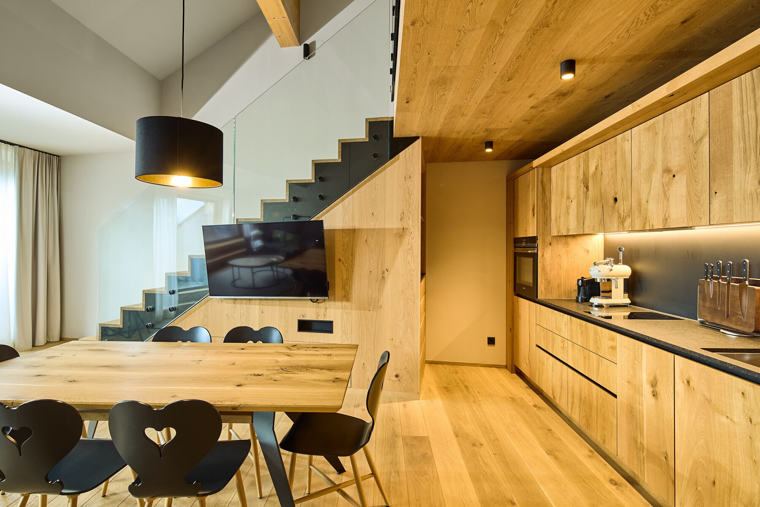 A modern kitchen with wooden cabinetry, a built-in oven, and a coffee machine.