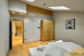 A bedroom with a bed, a wardrobe, a painting, and a skylight. - 8038 Alpin Retreat Grand Maisonette 38 (Schröcken)