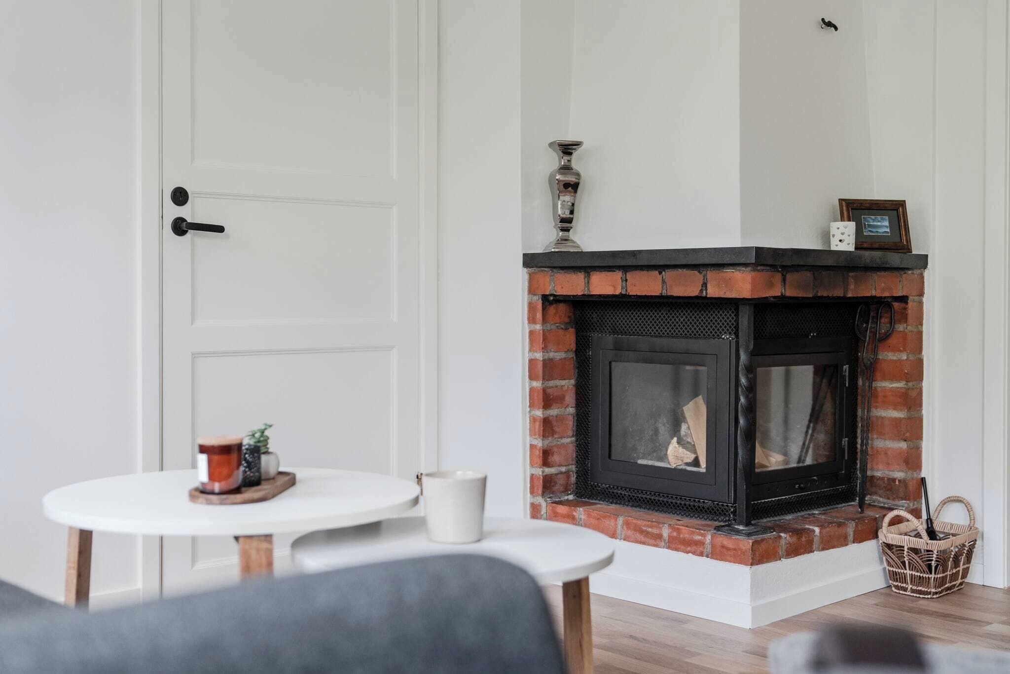 A room with a fireplace, a white door, and a small table with a cup and a decorative item.