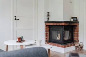 A room with a fireplace, a white door, and a small table with a cup and a decorative item.
