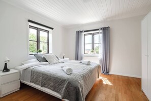 A bedroom with a bed, nightstands, a window with curtains, and a view of greenery outside. - Linneby , fri Parkering (Uddevalla)