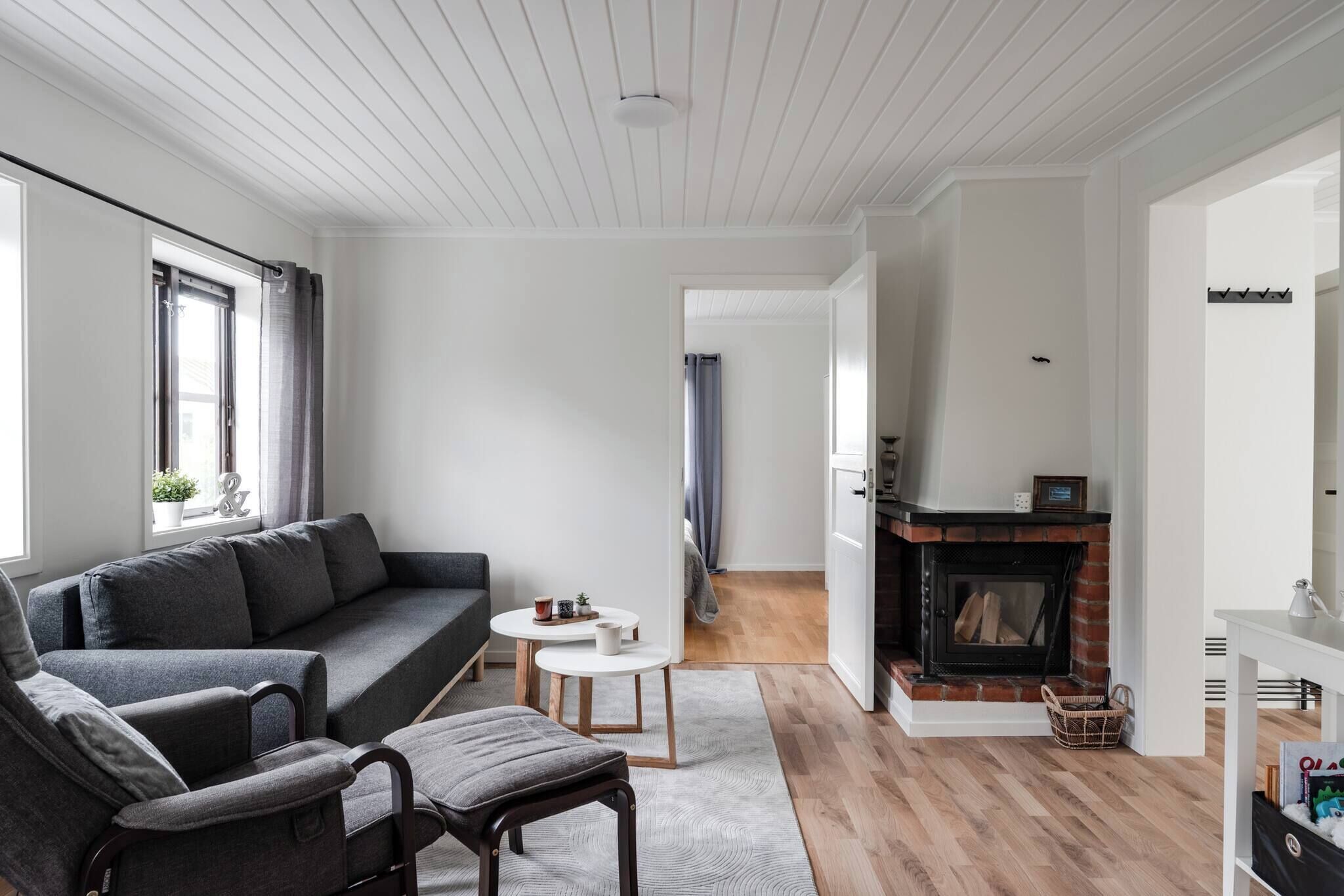 A modern living room with a grey sofa, a small round table, and a fireplace.