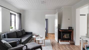 A modern living room with a grey sofa, a small round table, and a fireplace.