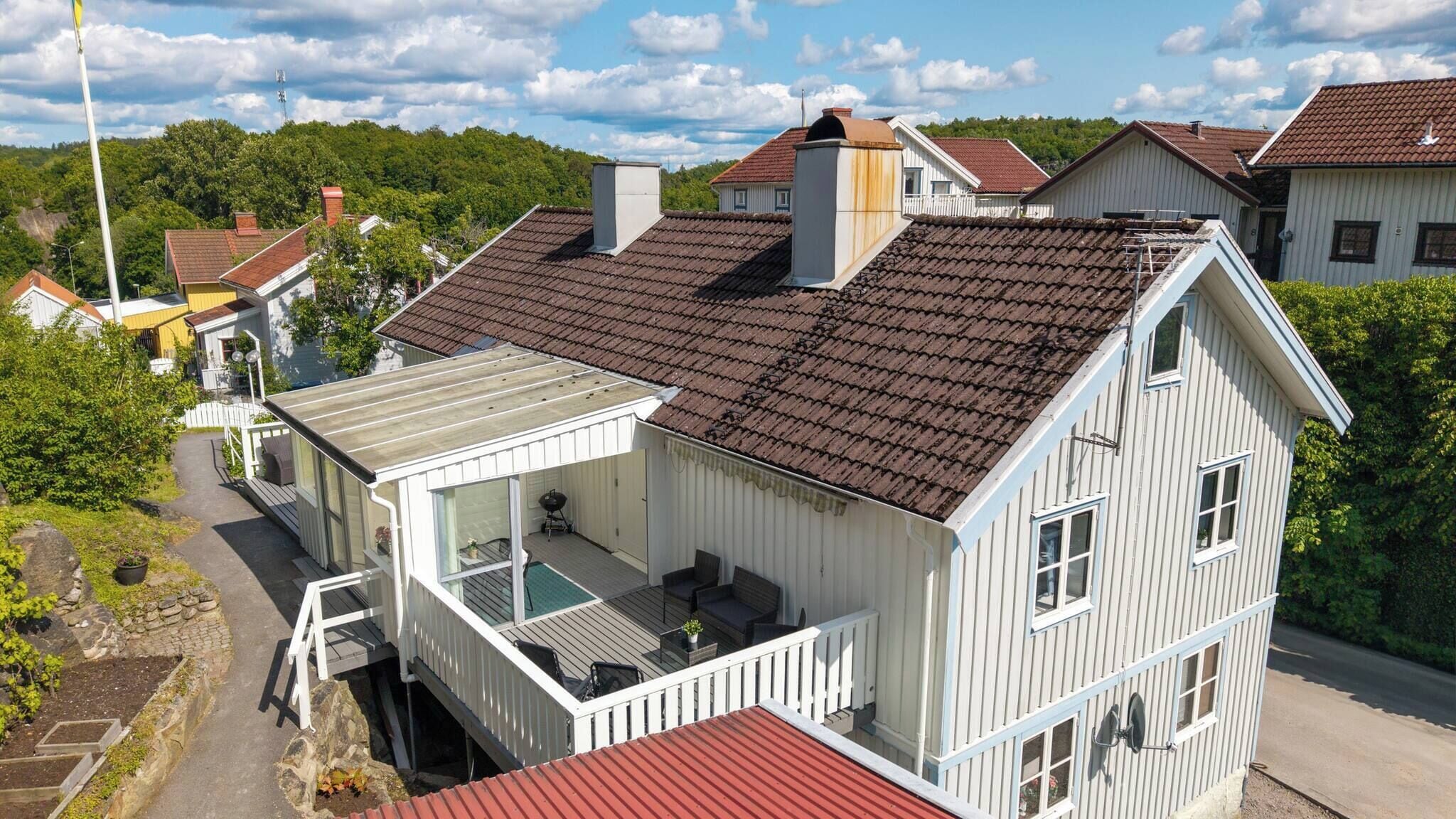 A two-story house with a red roof, a balcony, and a small deck area.