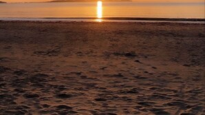Ein Strand bei Sonnenuntergang am Horizont.