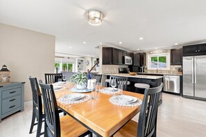 A modern kitchen with dark cabinets, stainless steel appliances, and a dining area with a wooden table and chairs.