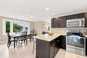 Una cocina moderna con armarios oscuros, electrodomésticos de acero inoxidable y una isla grande con un cuenco de fruta.