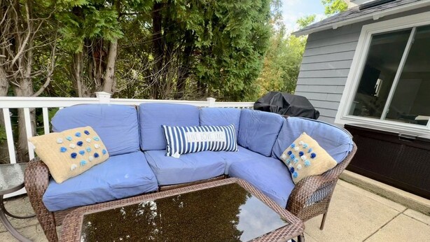 Um sofá azul com uma mesa de centro trançada, cercado por móveis de exterior.