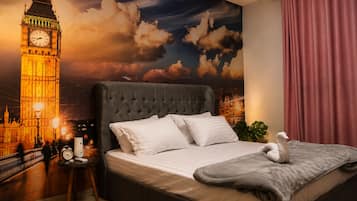 A bedroom with a large bed, a clock, a lamp, and a wall mural of a famous clock tower.