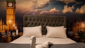A bed with a tufted headboard, two pillows, and a swan-shaped towel.