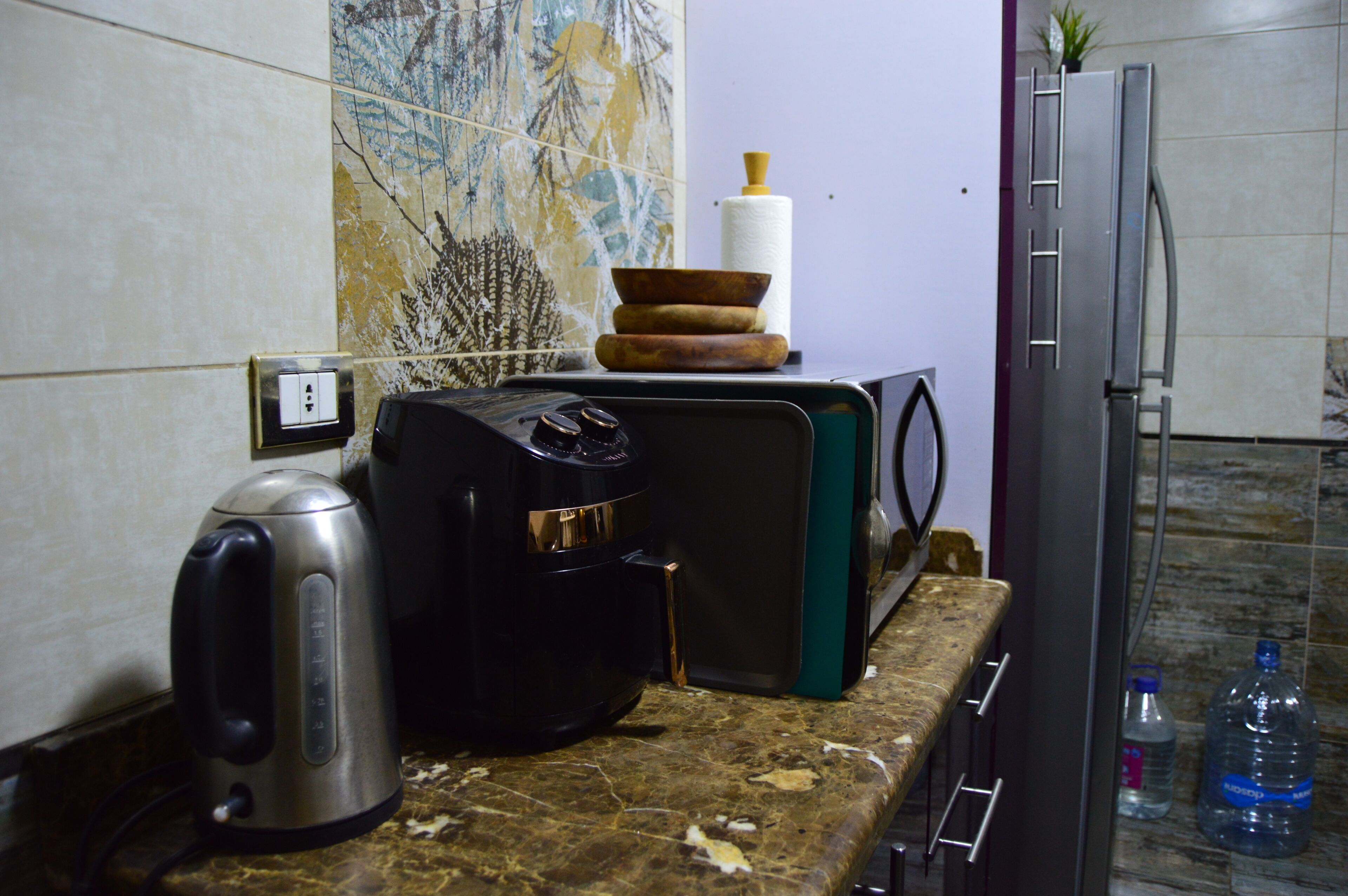 A kitchen counter with a kettle, coffee maker, and a stack of bowls.