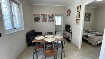 Un espace de vie compact comprenant un coin repas, un canapé, un téléviseur et un lit.
