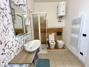 Ein Badezimmer mit Waschbecken, Toilette, Bidet, Dusche und Handtuchhalter.