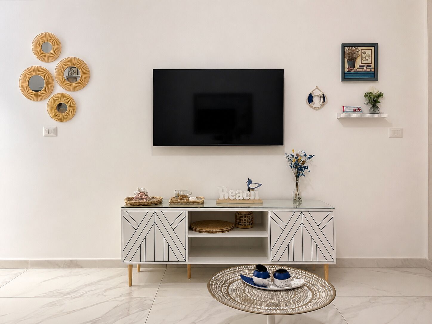 Una sala de estar moderna con un televisor de pantalla plana montado en la pared, una consola blanca con diseños geométricos y arte decorativo en la pared.