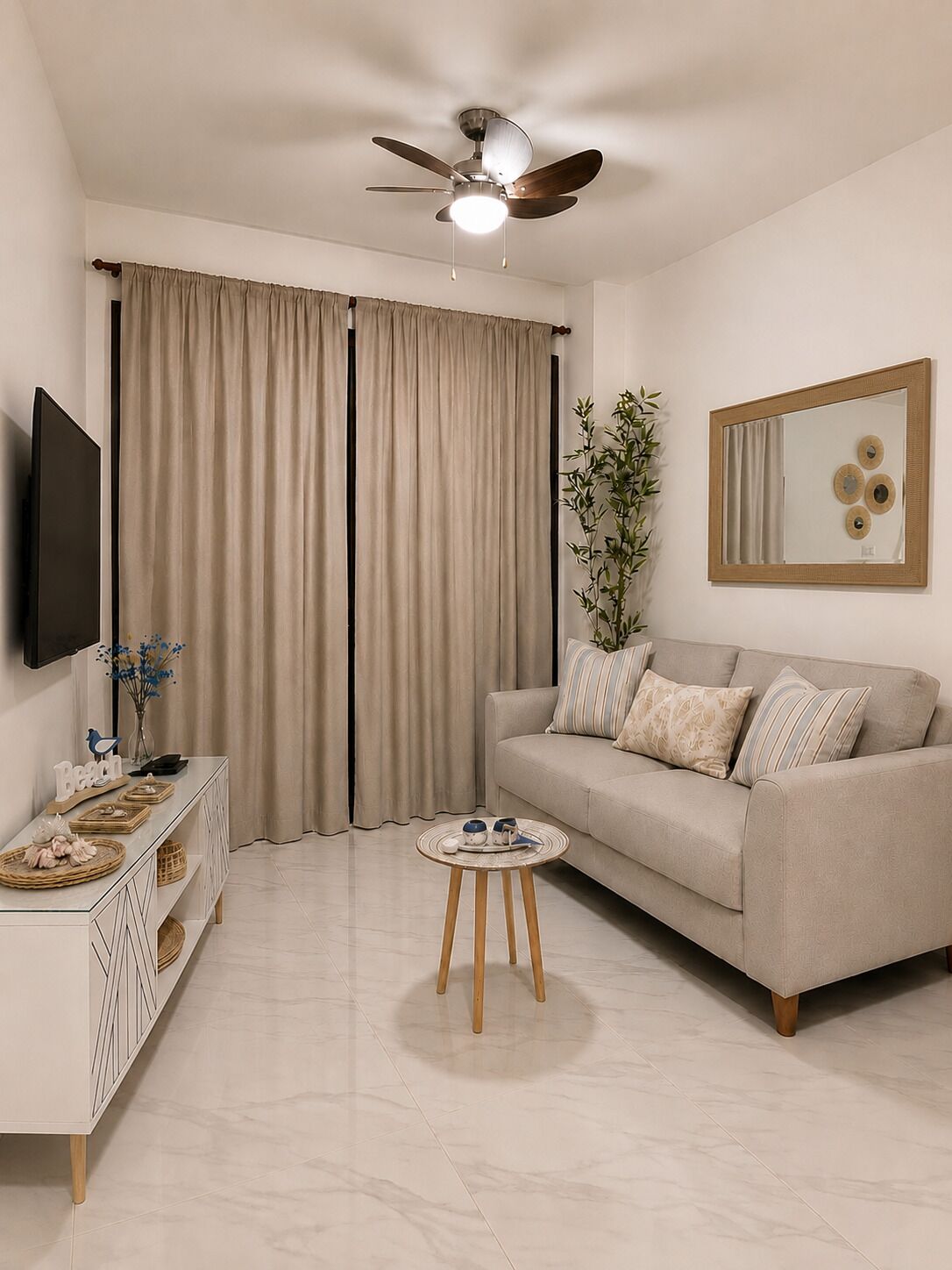 A living room with a sofa, a coffee table, a TV, and a ceiling fan.
