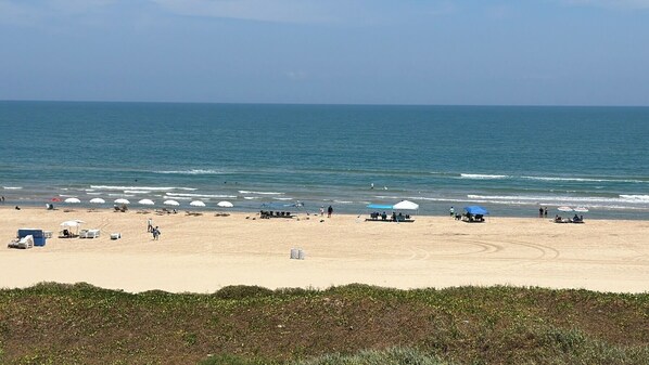 Ein Strand mit Sonnenschirmen, Zelten und Menschen.