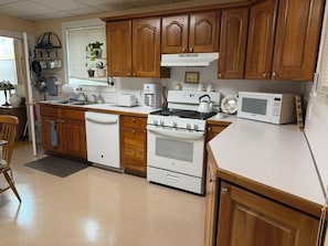 A kitchen with wooden cabinets, a stove, a microwave, and a sink. - 3-bedroom apartment with garage on welcoming Tipperary Hill in Syracuse (Syracuse)