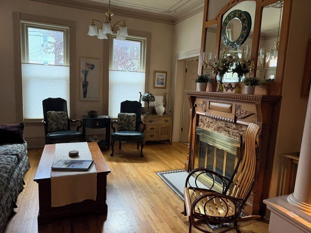 A traditional living room with a fireplace, wooden furniture, and a chandelier.