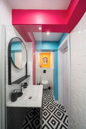 Een moderne badkamer met een wit wastafelmeubel, spiegel en een zwart-wit betegelde vloer.