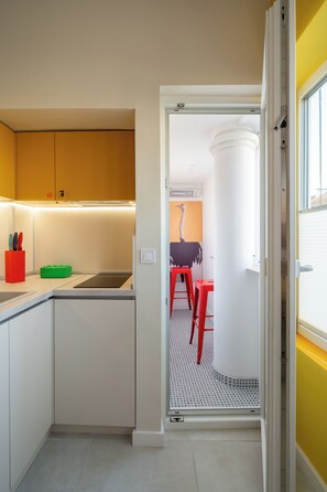 Een moderne keuken met witte kastjes, een zwart aanrecht en een rode kruk.