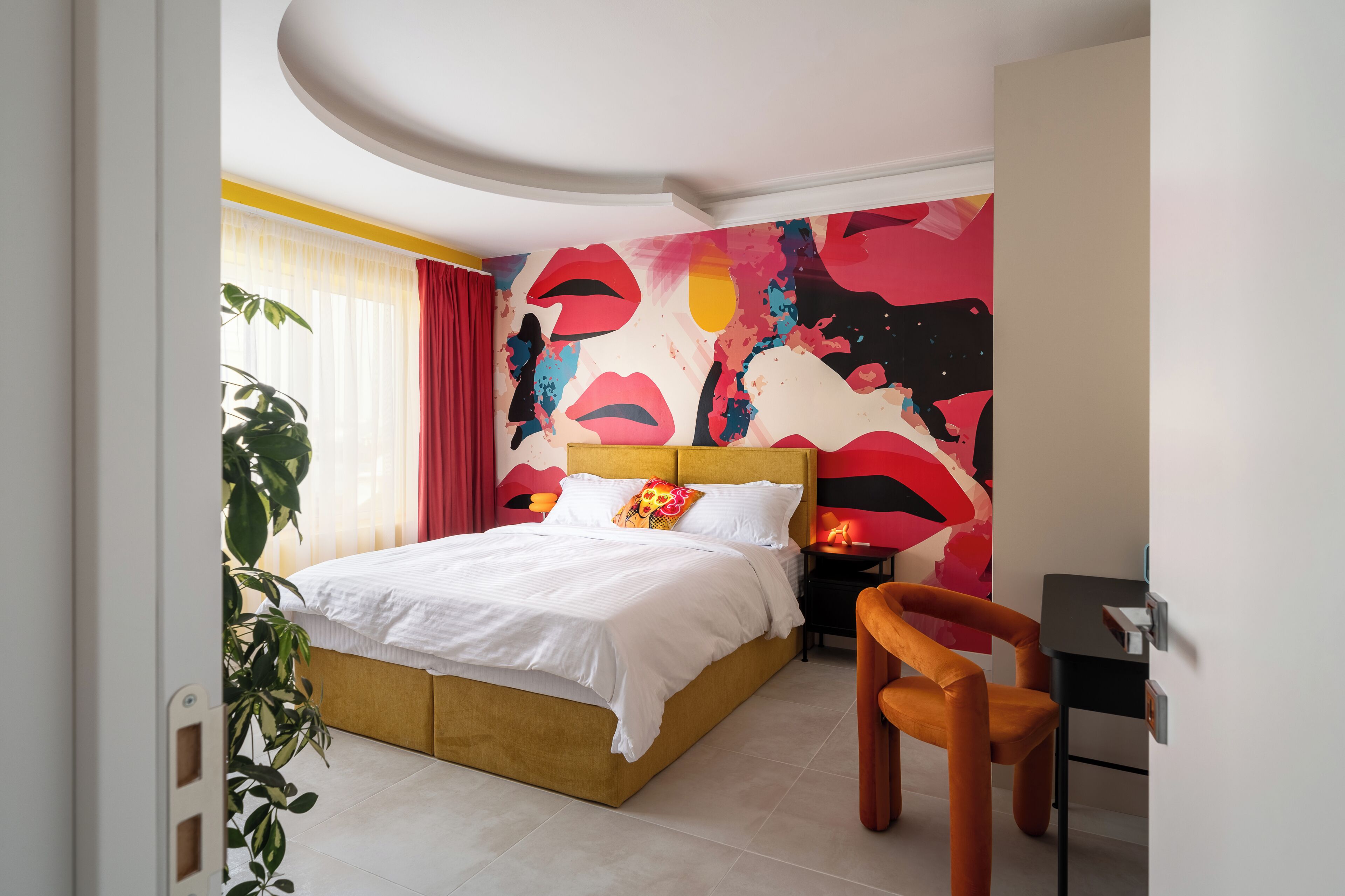 Une chambre à coucher moderne avec un lit, une table de chevet, une chaise et un grand tableau abstrait accroché au mur.