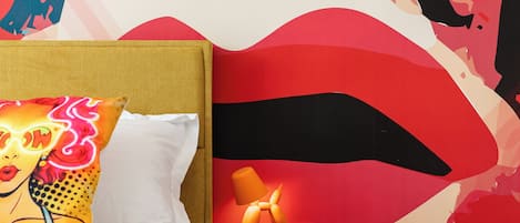 A bedroom with a bed, a nightstand, and a wall with abstract art.