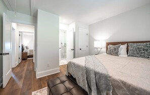 A bedroom with a large bed, a bedside table, a nightstand, a bench, and a walk-in closet. - Blue Ridge Mountains View - House & Resort (Boone)