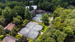 An aerial view of a residential area with multiple tennis courts surrounded by dense greenery and houses. - Blue Ridge Mountains View - House & Resort (Boone)