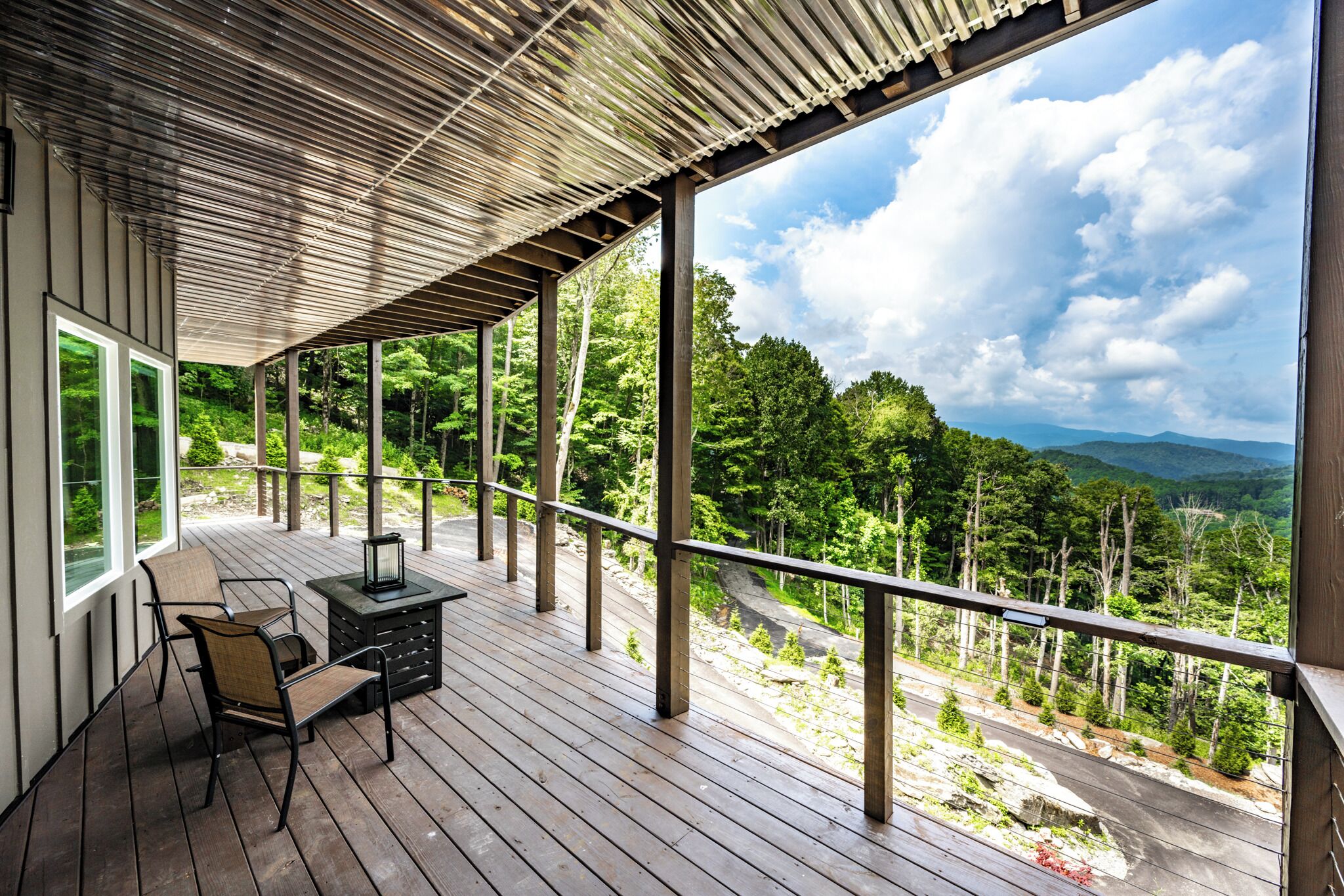 Une terrasse extérieure couverte offrant une vue sur un paysage boisé.