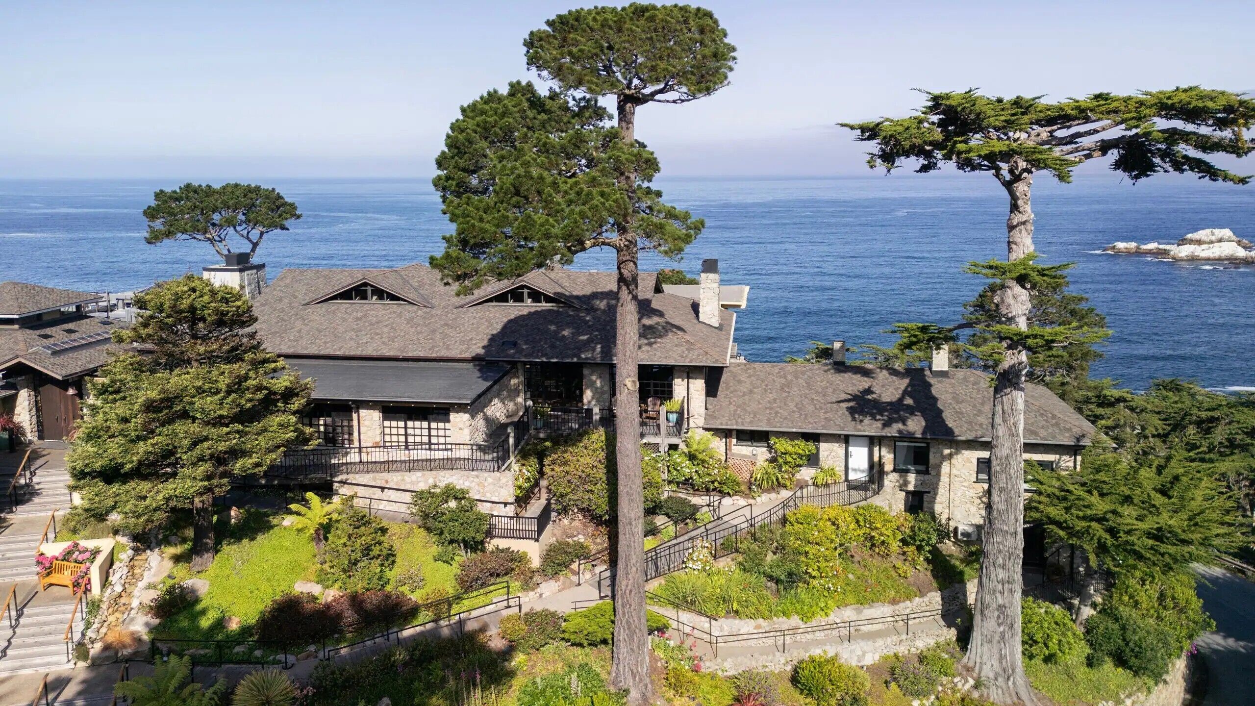A coastal property with multiple buildings, a prominent tree, and a view of the sea.