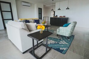 A living room with a sofa, a small table with a vase of flowers, a patterned rug, and a patterned armchair.