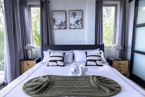 A hotel room with a large bed, two bedside tables, a window with curtains, and two framed pictures on the wall.