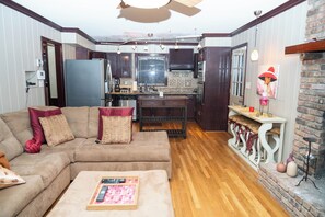 A compact living space with a sofa, a coffee table, a kitchen area, and a dining table. - Elegant Home with Spacious Bedrooms & Lush Yard (East Point)
